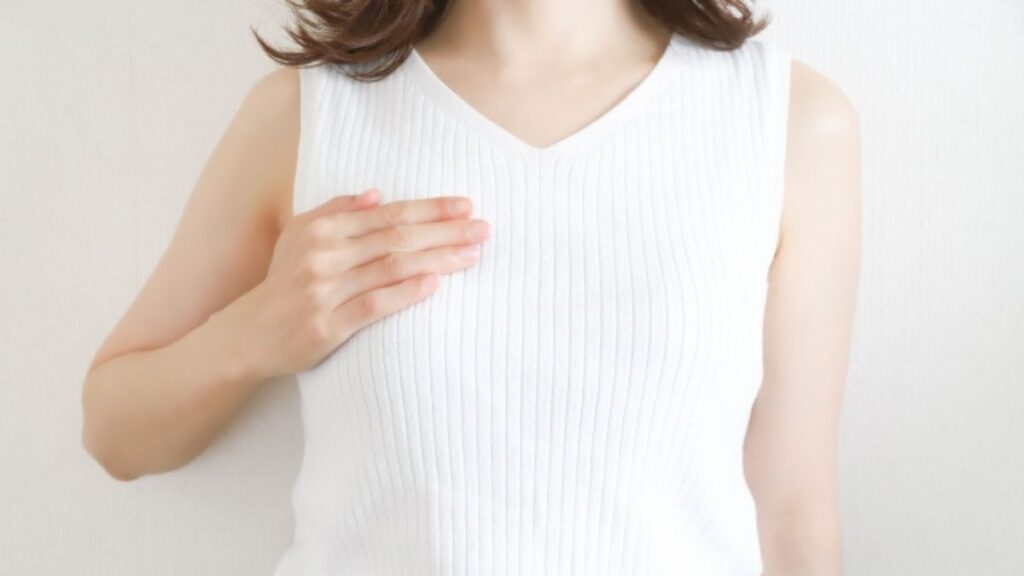 白キャミソールで胸に手をあてる女性