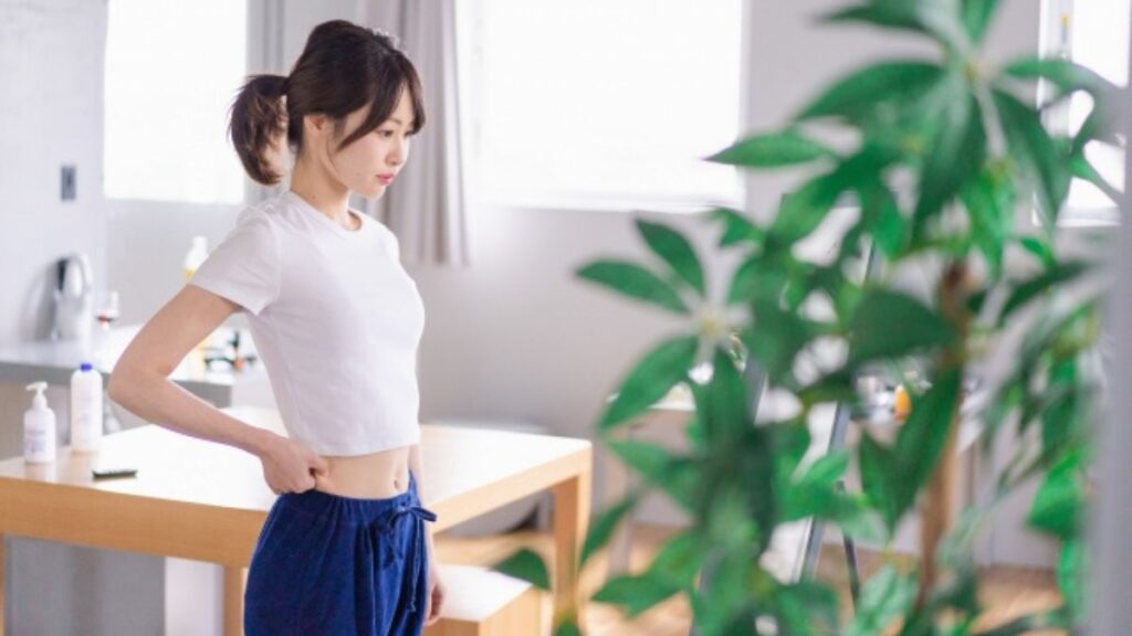 鏡の前に立ってスタイルをチェックする女性